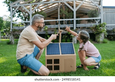 Dad and girl plying with house with solar panels on roof, learning about solar energy. Rooftop solar or photovoltaic system. Sustainable future for next generation. - Powered by Shutterstock