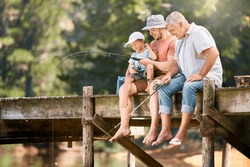 Dad, Grandfather And Teaching Child Fishing At Lake Together For Fun Bonding, Lesson Or Activity In Nature. Father, Grandpa And Kid Learning To Catch Fish With Rod By Water Pond Or River In Forest