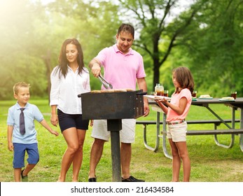 Dad Grilling Food For Wife And Kids At Outdoor Cookout