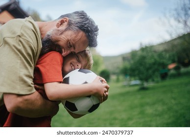 Dad having fun with young son, playing football, running and catching each other. Playing on a lawn in front of their house. Fatherhood and Father's Day. - Powered by Shutterstock