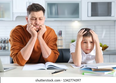 Dad Helping His Son With Difficult Homework Assignment In Kitchen