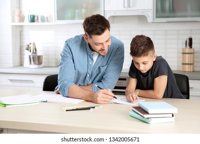 Dad Helping His Son With Homework In Kitchen