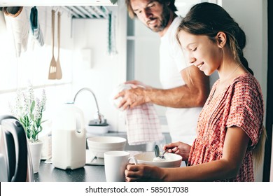 Dad With His 10 Years Old Kid Girl Cooking In The Kitchen, Casual Lifestyle Photo Series. Child Making Breakfast With Parent Together. Cozy Homely Scene.