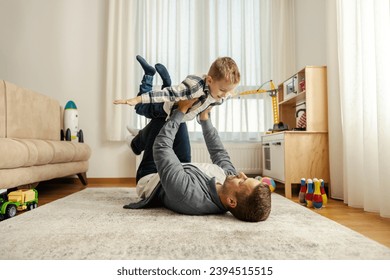 A dad and his boy are playing airplane at home. - Powered by Shutterstock