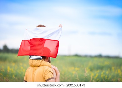 Dad with his little son on his shoulders walking in the field holding flag of Poland. Father's day in Poland. Polish Flag Day. Independence Day. Love Poland, travel concept. Selective focus. - Shutterstock ID 2001588173
