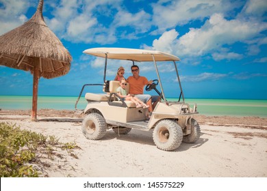 Dad and his two daughters driving golf cart on a tropical beach