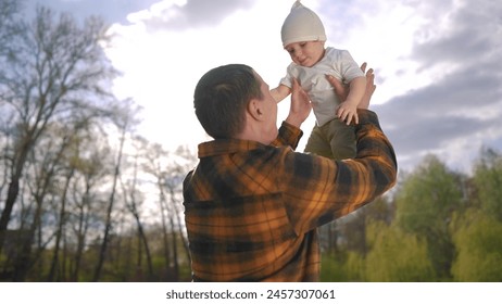 dad holds the baby in his arms. concept of happy dad with child. young happy dad holding his little son in his arms against the backdrop of a summer forest. little kids dad's - Powered by Shutterstock