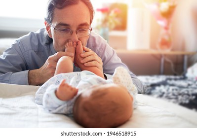 Dad Kissing The Baby's Feet. Baby Feet In Parents Hands. Soft Focus.