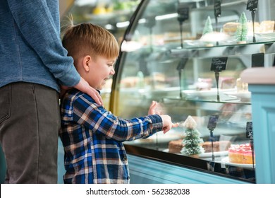 Dad and little son choosing and pointing at sweet cake in showcase స్టాక్ ఫోటో