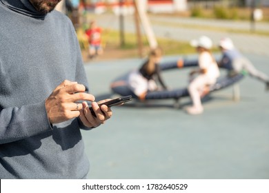 Dad Looks At His Phone And Does Not Follow Children In The Playground