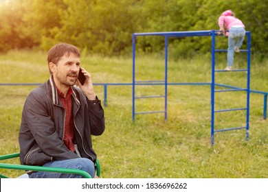 Dad Looks At His Phone And Does Not Follow Children In The Playground