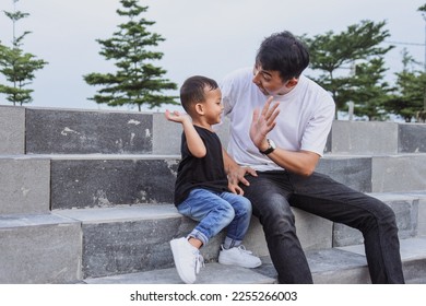 Dad making high five with little son, having fun at park, enjoying pleasant conversation together.  - Shutterstock ID 2255266003