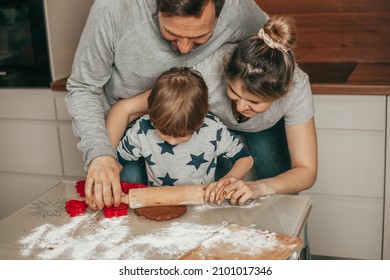 Dad, mom and child together with hands using rolling pin roll out dough on table at home, cozy kitchen, happy hours together, teamwork. Joint hobby. Happy family. Christmas moment