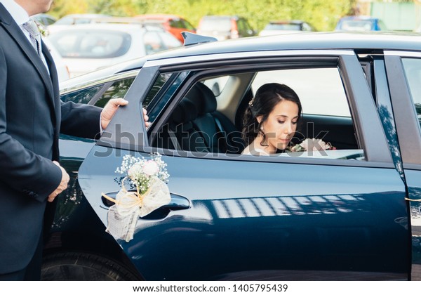 Dad opens the car door for\
the bride. Portrait of the bride with his father. bride in a car\
window