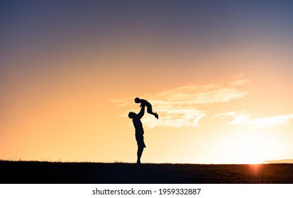 Dad Playing With His Son Lifting Him Up In The Air Silhouette. Father Son Relationship Concept. 