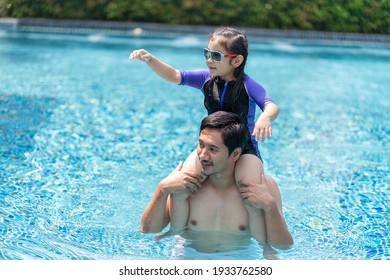 Dad Plays With His Daughter In The Pool During The Summer Vacation.