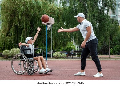 Dad plays with his disabled son on the sports ground. Concept wheelchair, disabled person, fulfilling life, father and son, activity, cheerfulness, basketball - Powered by Shutterstock