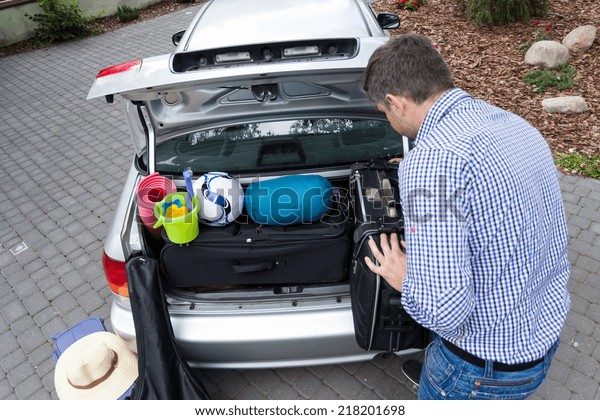 Dad preparing\
car trunk for holiday,\
horizontal