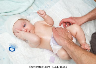 Dad Puts A Diaper On The Baby.