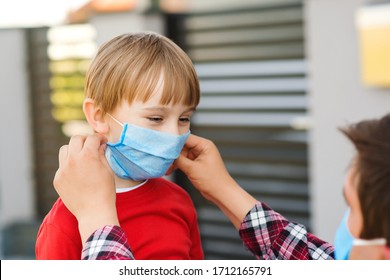 Dad Puts On His Kid Face Mask Outdoors. Coronavirus Quarantine. Coronavirus Epidemic, Virus Symptoms. Family Wearing Face Mask For Protection During The Quarantine. Coronavirus Outbreak.