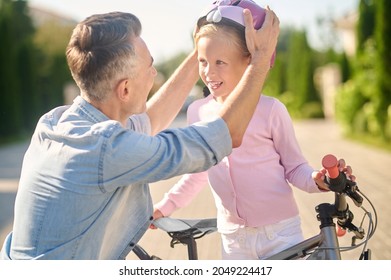 Dad Putting His Daughter On Bicycle Helmet