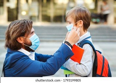 Dad putting on a protective mask on his son's face outdoors. Schoolboy is ready go to school. Cute boy with backpack. Back to school concept. Medical mask to prevent coronavirus. Coronavirus pandemic