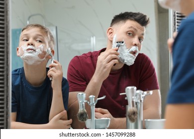 Dad Shaving And Son Imitating Him At Mirror In Bathroom