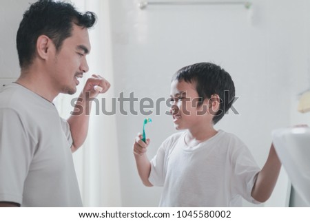 Dad And Son Are Brushing Their Teeth Together In The Morning Dad And Son Are Brushing Their Teeth Together In The Morning
