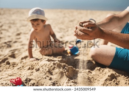 dad and son are building a sand castle on the beach. Hands and sand slipping through fingers close-up. Games on the beach on a hot summer day