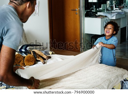 Dad and son changing bed sheet together