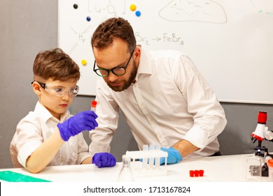 dad and son the child stayed at home conduct experiments on a white table, behind them on the wall is a white Board magnetic-marker, classes with a child at home,  entertainment with children in self - Powered by Shutterstock