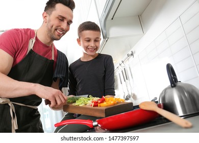 Dad And Son Cooking Together In Kitchen