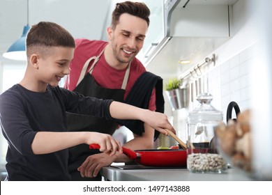 Dad And Son Cooking Together In Kitchen