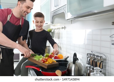 Dad And Son Cooking Together In Kitchen