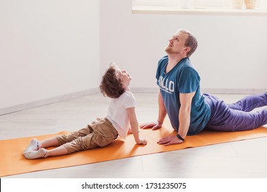 Dad Son Do Sport At Home. The Father Teaches Child A Healthy Lifestyle. Parenthood Modern Fatherhood. Love Harmony  Leisure Family Apartment Activity. Quarantine Self-isolation Yoga Asana Cobra Pose