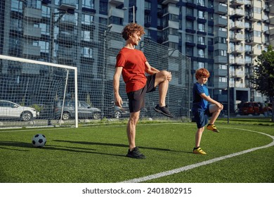 Dad and son doing physical workout and warming legs up before football training - Powered by Shutterstock