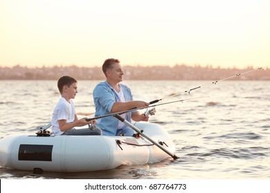 Dad And Son Fishing From Inflatable Boat On River