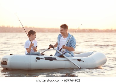 Dad And Son Fishing From Inflatable Boat On River