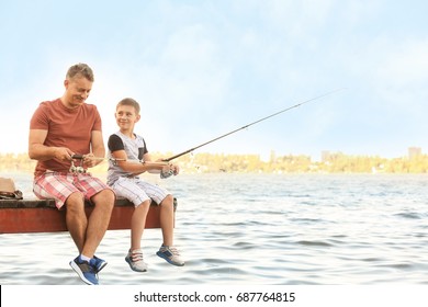 Dad And Son Fishing From Pier On River