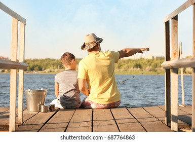 Dad And Son Fishing From Pier On River