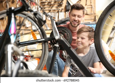 Dad And Son Fixing Bicycle In Garage