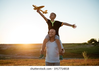 Dad and son launch a plane at sunset in summer