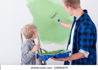 Dad And Son Painting Wall In Child's Room