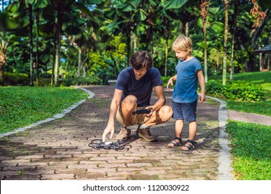 Dad and son playing with drone, man and boy playing with flying drone in sunny autumn garden, happy young boy and father playing with unmanned aerial vehicle, spending time together. - Powered by Shutterstock