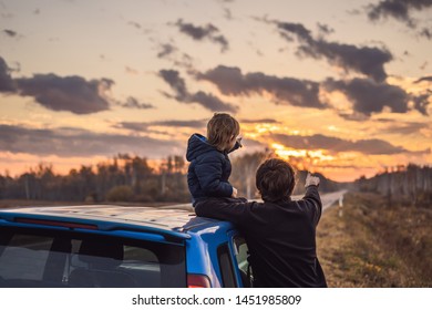 Dad And Son Are Resting On The Side Of The Road On A Road Trip. Road Trip With Children Concept