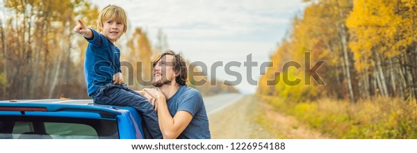 Dad and\
son are resting on the side of the road on a road trip. Road trip\
with children concept BANNER, LONG\
FORMAT