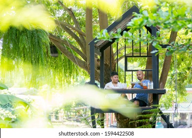 Dad And Son Are Sitting Happily And Comfortably Eating In The Treehouse.