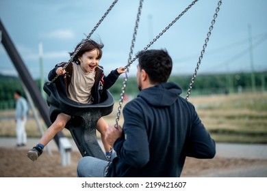 Dad and son swing on a swing. Happy family. The father spends time with the children, the father walks with the child in the summer in the park - Shutterstock ID 2199421607