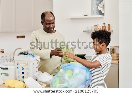 Dad and son throwing garbage in packet together