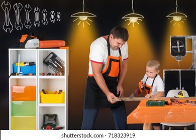 Dad and son work together in the carpentry shop.Father teaches his son to cut wooden planks.